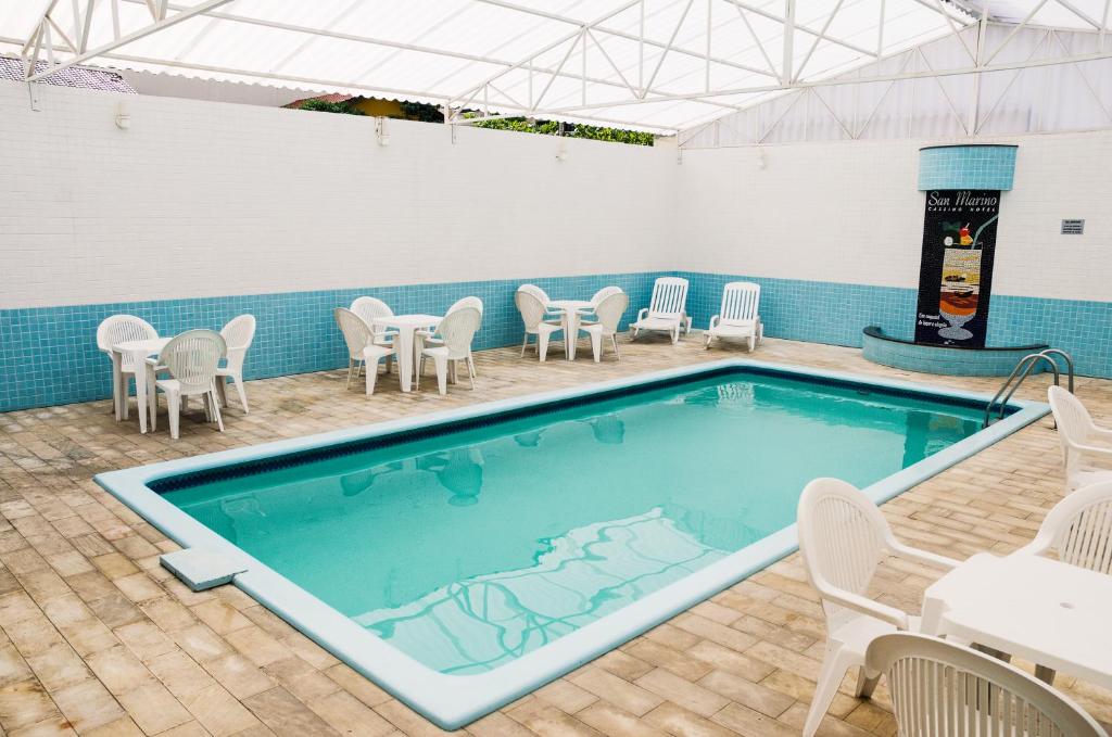 a pool with chairs and a table and a table and chairs at San Marino Cassino Hotel in Balneário Camboriú