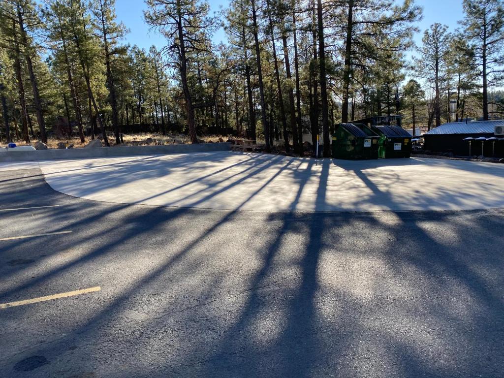 a parking lot with trees and shadows on the ground at Motel In The Pines in Munds Park