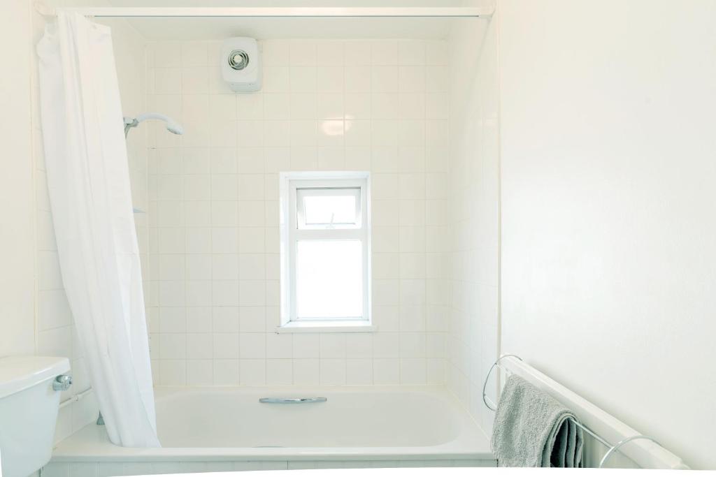 a white bathroom with a tub and a window at Avocet House in Wells next the Sea