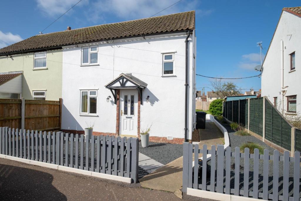 a white house with a white picket fence at Avocet House in Wells next the Sea