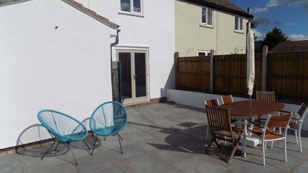 a patio with a wooden table and chairs at Avocet House in Wells next the Sea