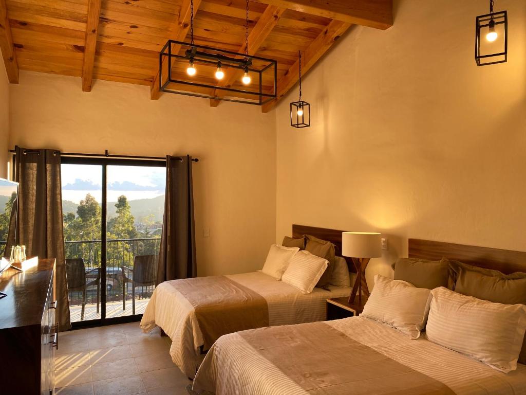 a bedroom with two beds and a balcony at Hotel Quinta del Bosque in Mazamitla