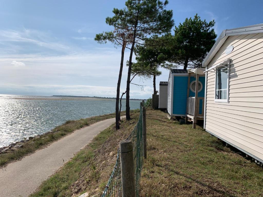 a house next to a road next to the water at Camping Les Violettes in La Faute-sur-Mer