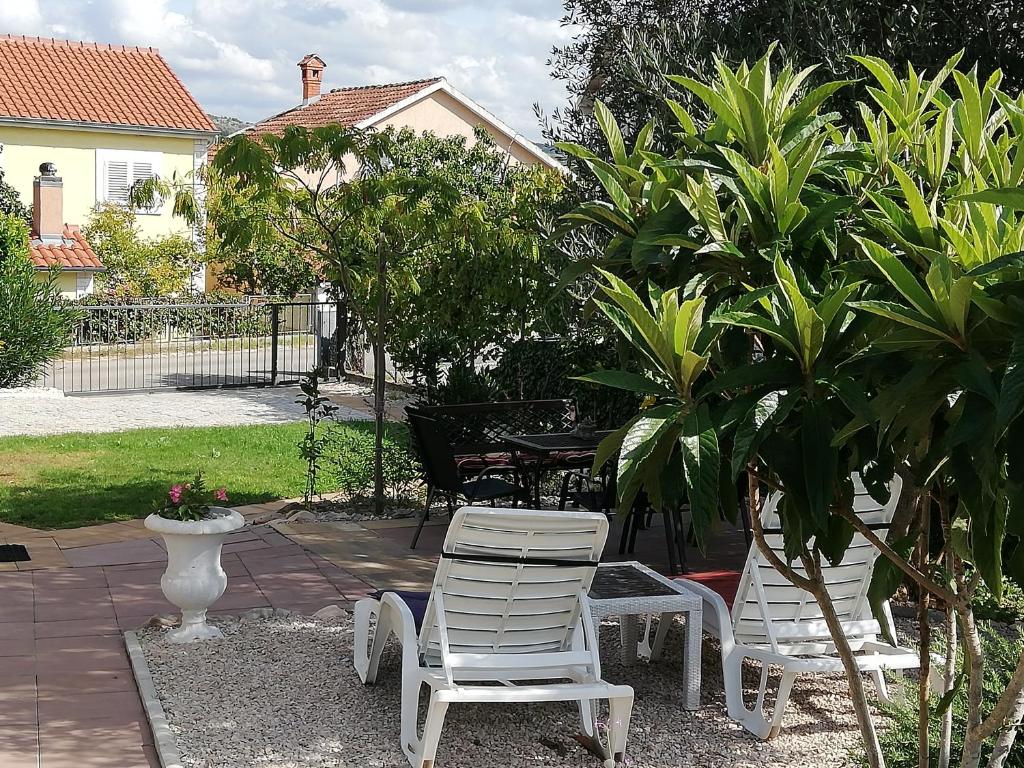 2 chaises blanches et une table dans un jardin dans l'établissement House Lily, à Šibenik