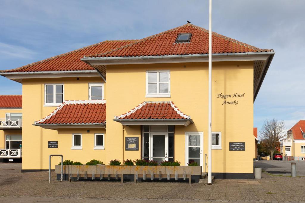 ein gelbes Haus mit rotem Dach in der Unterkunft Skagen Hotel Annex in Skagen