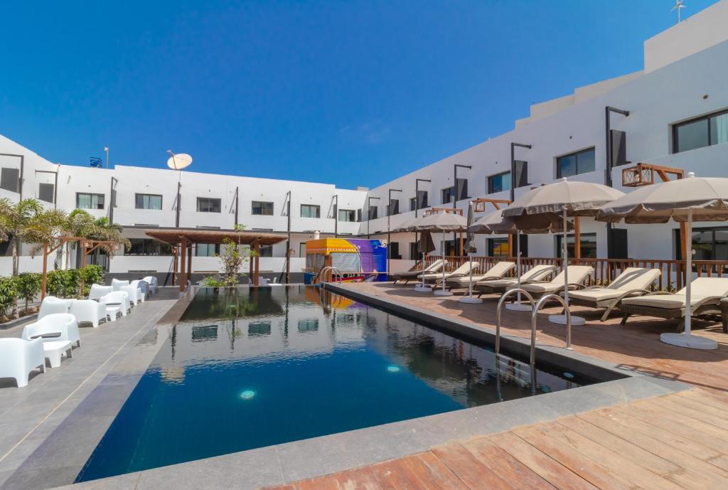 einen Pool im Hotel mit Stühlen und Sonnenschirmen in der Unterkunft ONOMO Hotel Dakar in Dakar
