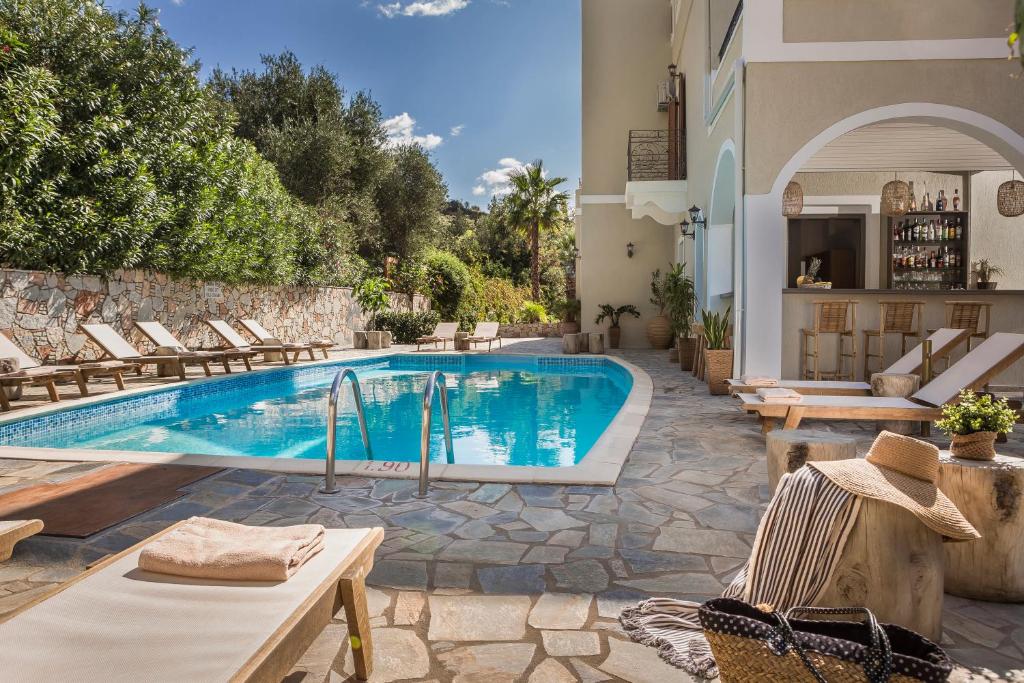 a swimming pool with lounge chairs and a house at La Signora Hotel in Lourdata