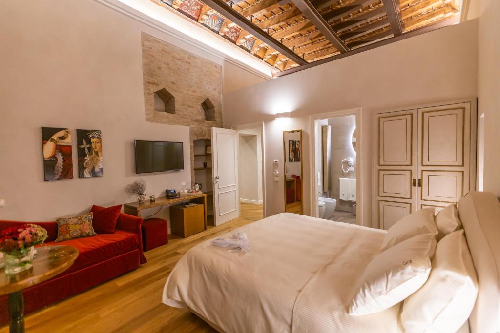 a bedroom with a large bed and a red couch at Dimora Storica Lo Svevo in Iesi