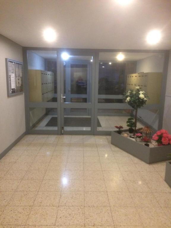 a lobby with glass doors and flowers on a tile floor at Monte Cristo in Metz