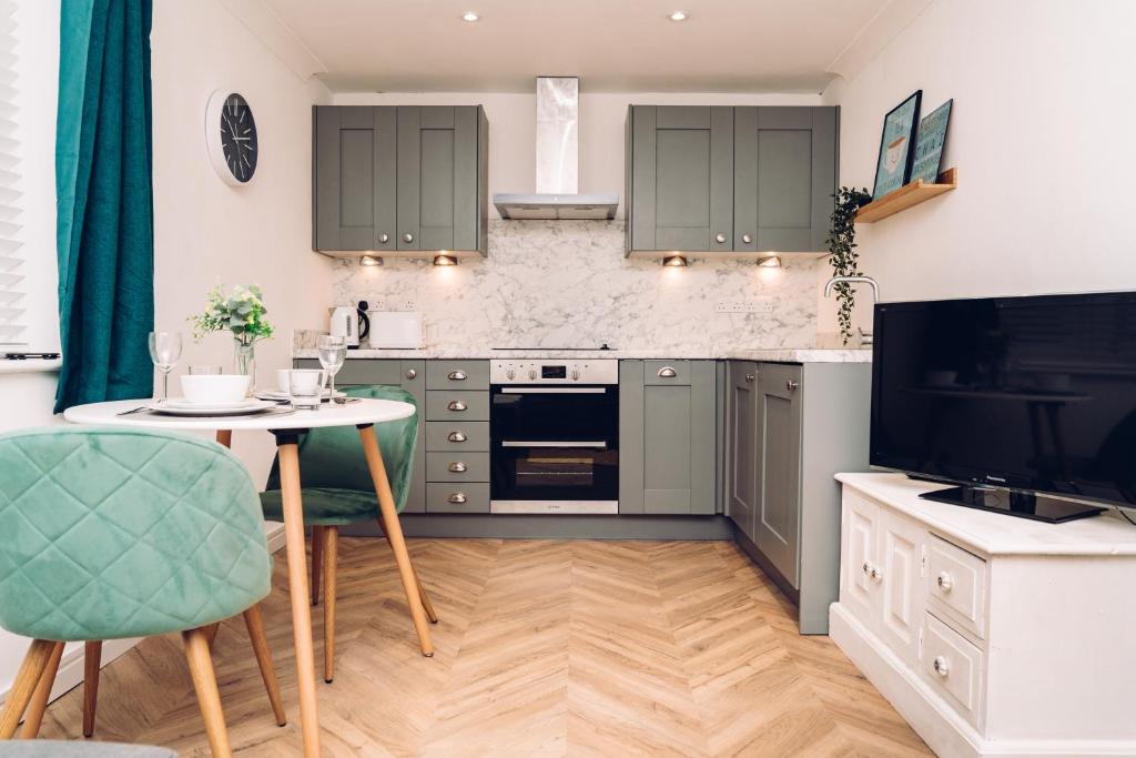 a kitchen with green cabinets and a table and a tv at Caroline Court - 1 Bedroom Apartment in Colchester