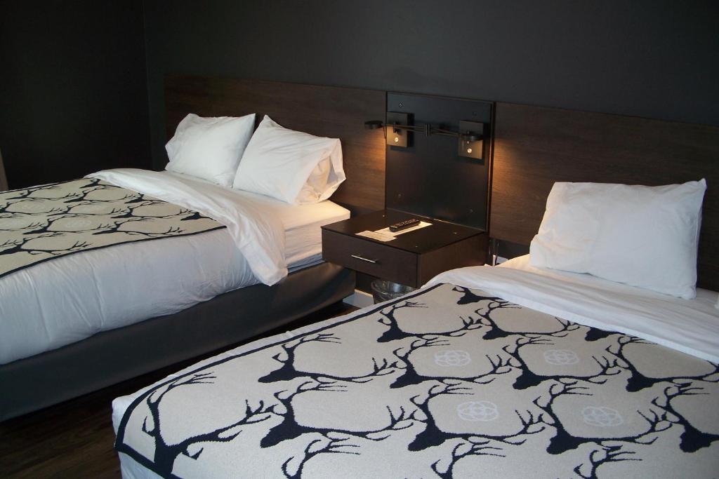 une chambre d'hôtel avec 2 lits et une table de nuit dans l'établissement Terra Nova Cabins, à West Yellowstone