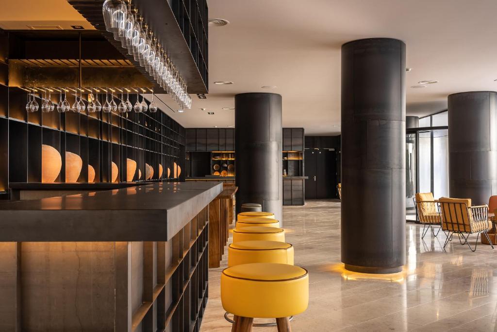 a lobby with a bar with yellow stools at 3HB Faro in Faro