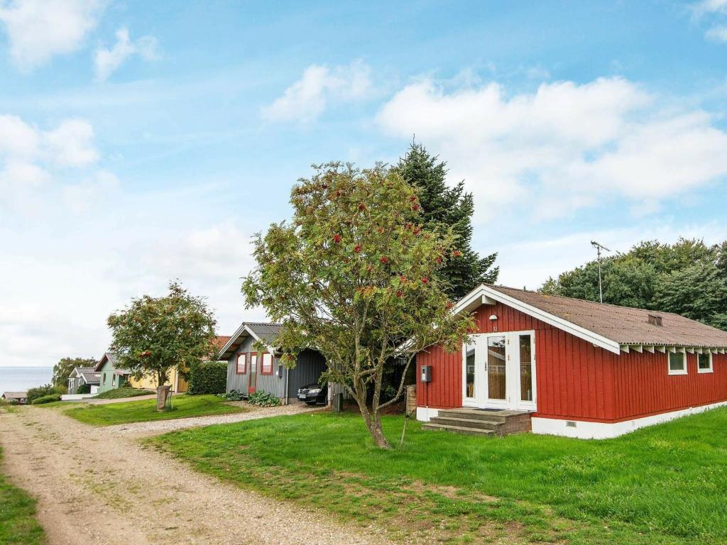 een rood huis met een boom naast een onverharde weg bij 6 person holiday home in Bjert in Binderup Strand