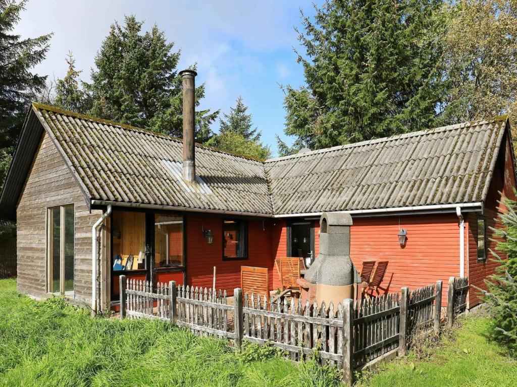 una pequeña casa roja con una valla de madera en 6 person holiday home in Vemb en Vemb