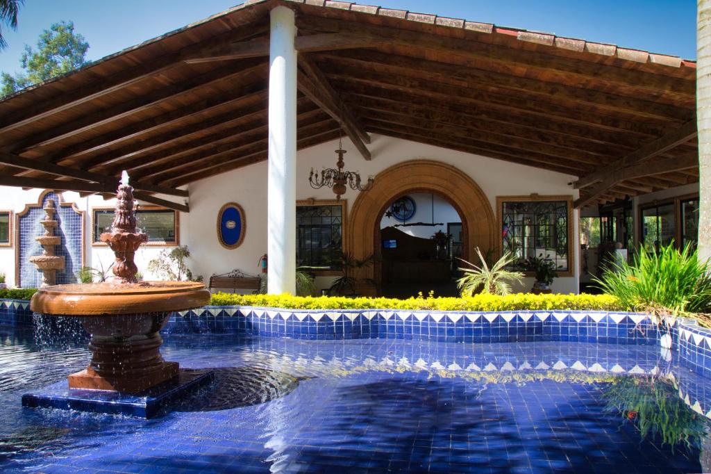 a swimming pool with a fountain in front of a house at Hotel El Rebozo in Valle de Bravo