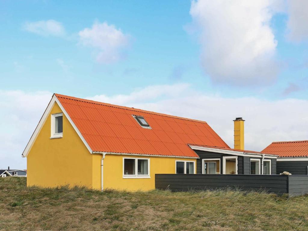 a yellow house with an orange roof on a hill at 6 person holiday home in Lemvig in Ferring