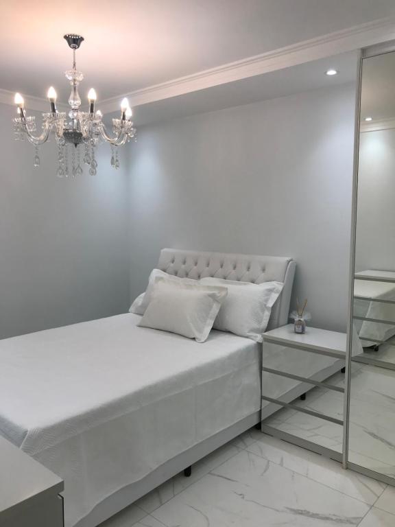 バルエリにあるApartamento Alphaville - Barueri/SPの白いベッドルーム(ベッド1台、シャンデリア付)