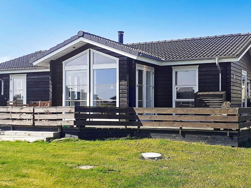 a black house with a large wooden deck in front of it at 6 person holiday home in Nordborg in Nordborg