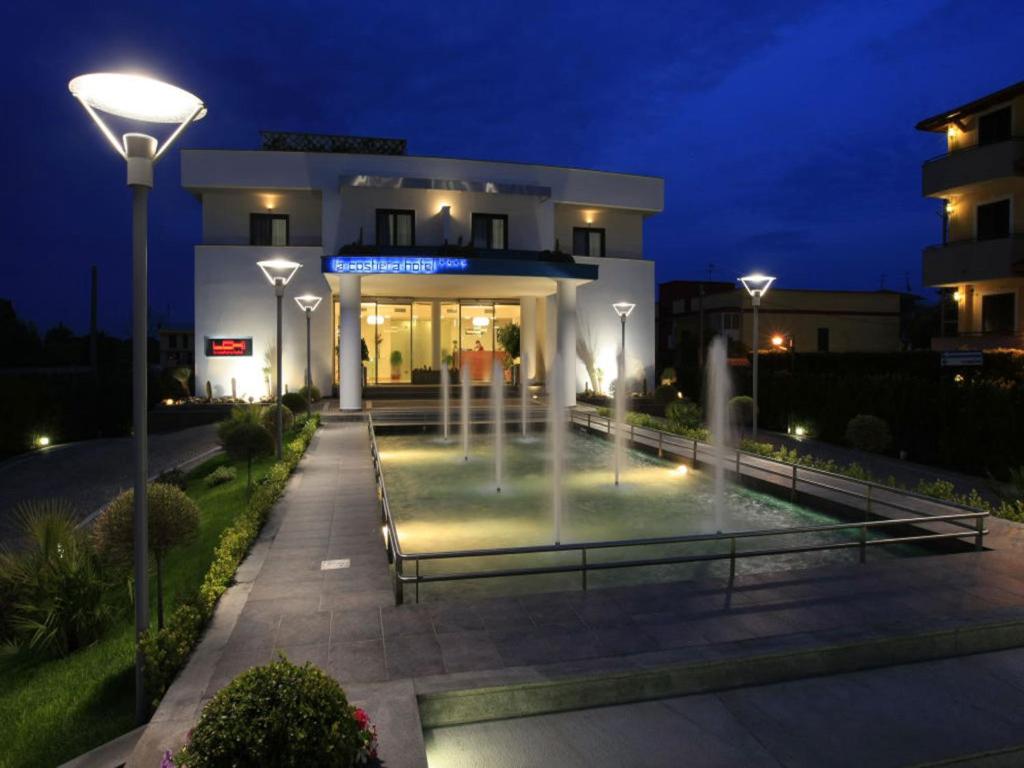 a building with a fountain in front of it at night at La Costiera Hotel in Marina di Varcaturo