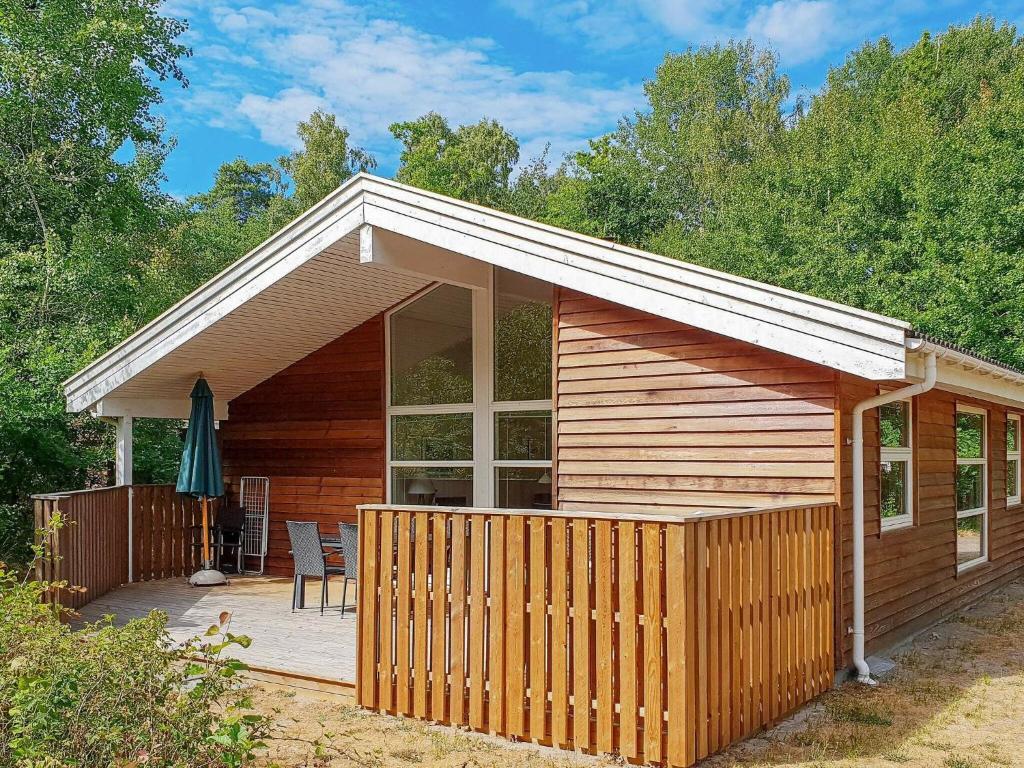 a wooden cabin with a deck and a patio at Four-Bedroom Holiday home in Hasle 1 in Hasle