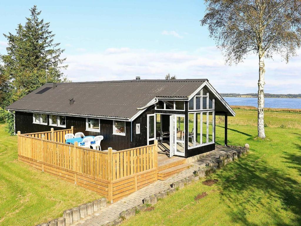 a black house with a porch and a deck at 4 person holiday home in H jslev in Højslev