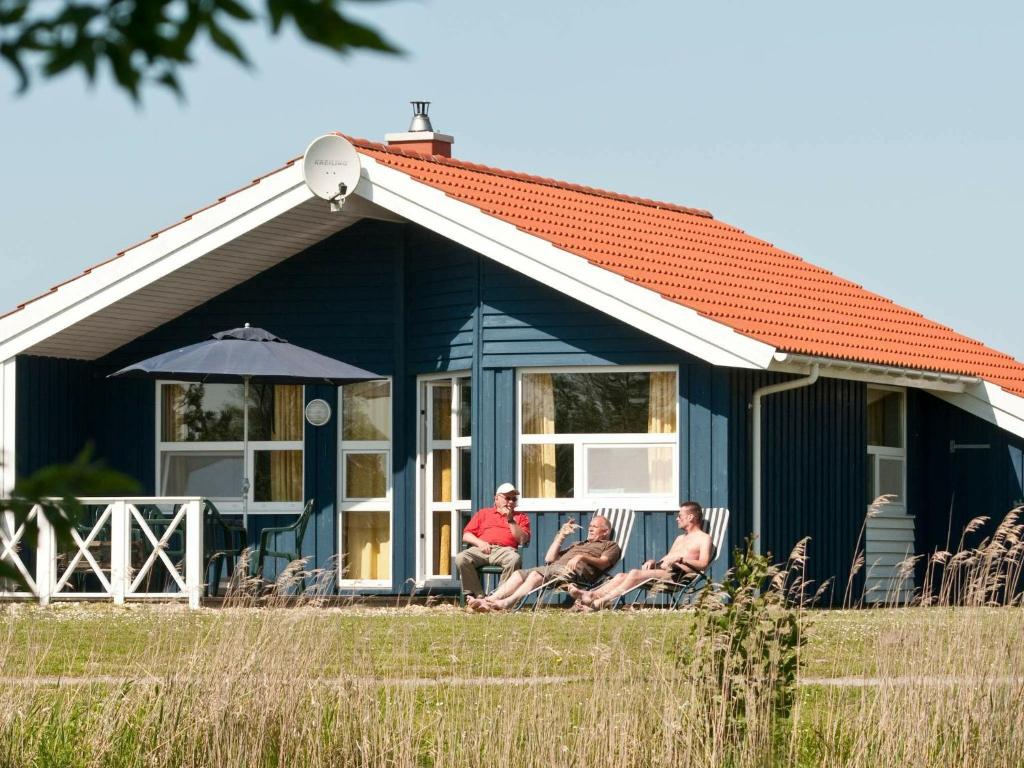 オッテルンドルフにある6 person holiday home in Otterndorfの青いコテージの前に座る3名