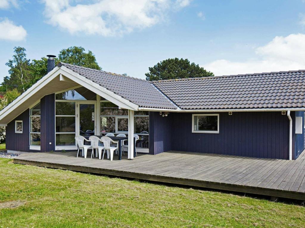 a house with a wooden deck with a table and chairs at 7 person holiday home in Asn s in Asnæs