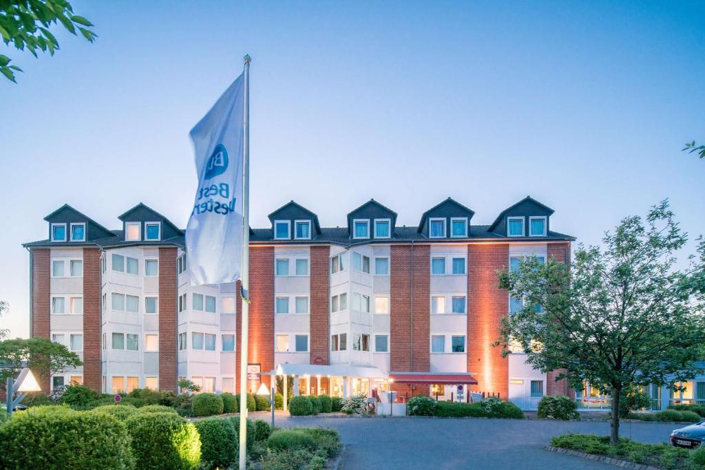 a hotel with a flag in front of it at Best Western Hotel Prisma in Neumünster