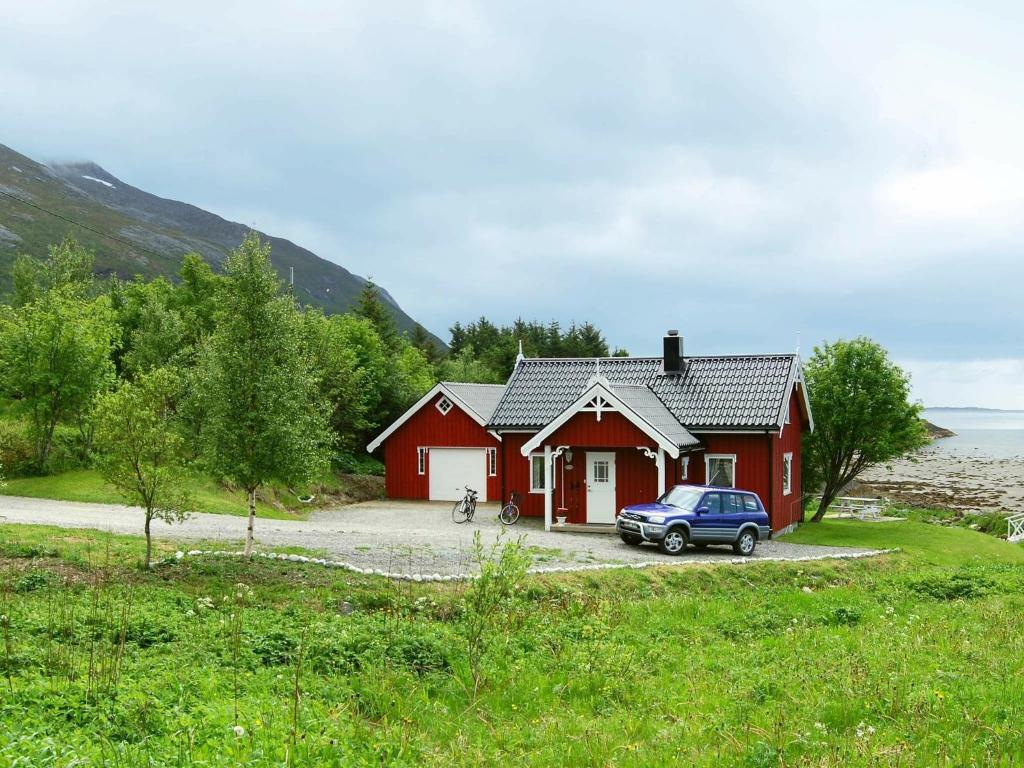 una casa roja con un coche aparcado delante de ella en 6 person holiday home in Vevelstad, en Vevelstad
