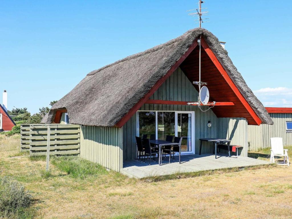 a small hut with a thatched roof with a table at 6 person holiday home in Hvide Sande in Hvide Sande