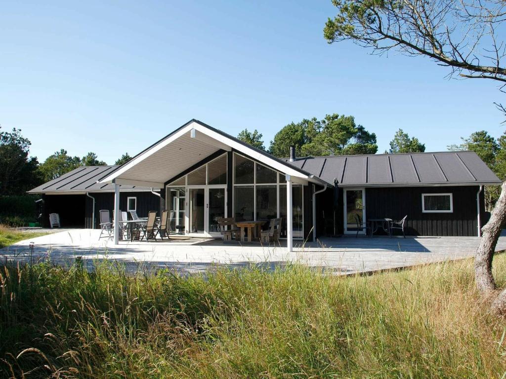 ein Haus mit einem schwarzen Dach und einer Terrasse in der Unterkunft 8 person holiday home in lb k in Ålbæk