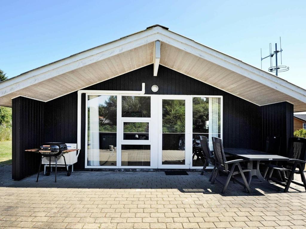 a black house with a patio with a table and chairs at 6 person holiday home in Hemmet in Falen