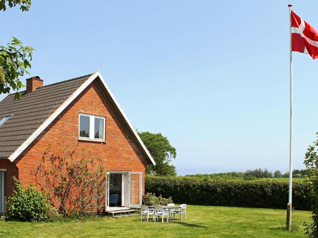 a house with a flag and tables and chairs at Three-Bedroom Holiday home in Gudhjem 2 in Gudhjem