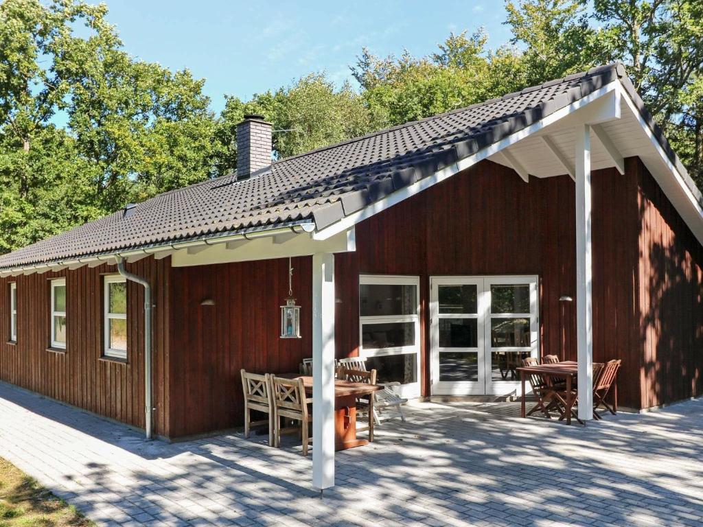 Oddeにある6 person holiday home in Hadsundのポーチとテーブル付きの大きな木造家屋