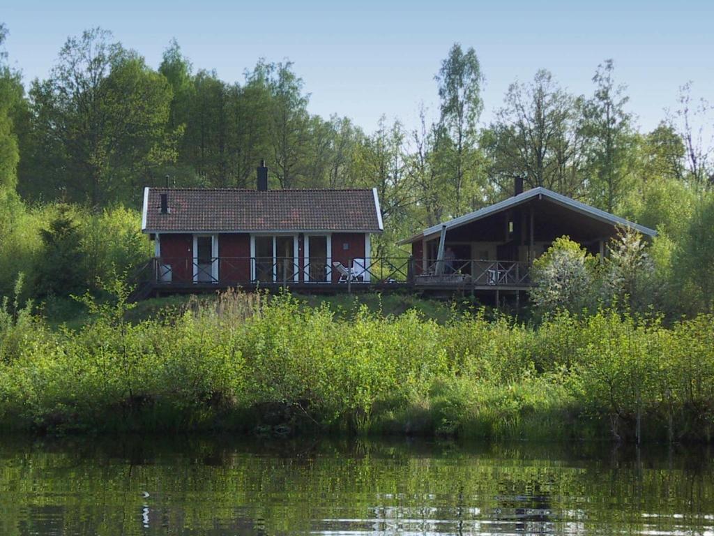 a red house with a deck next to a body of water at 8 person holiday home in GR NNA in Målskog