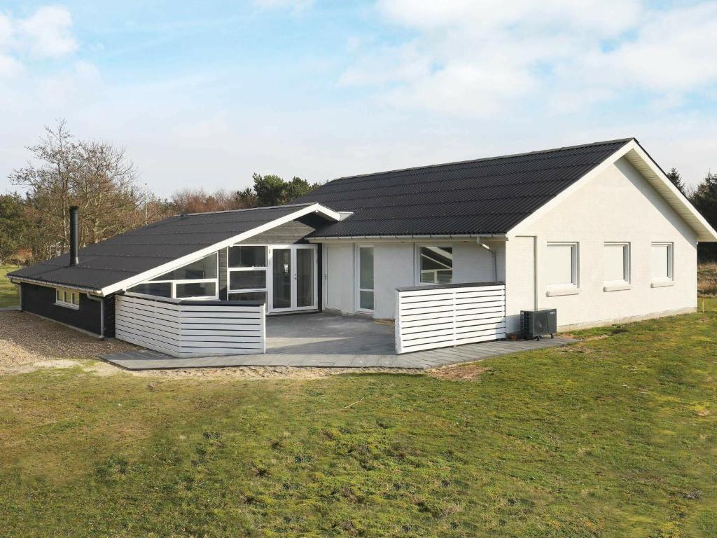 a white house with a black roof at 12 person holiday home in Vejers Strand in Vejers Strand