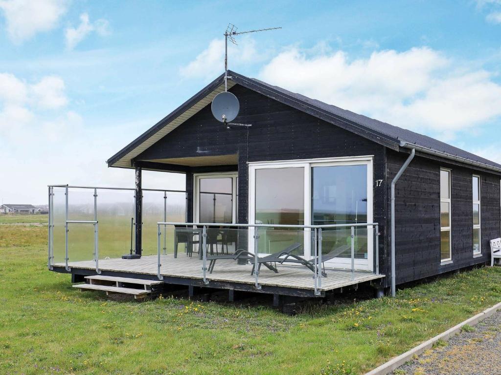 a small black house with a porch on a field at 4 person holiday home in Harbo re in Harboør