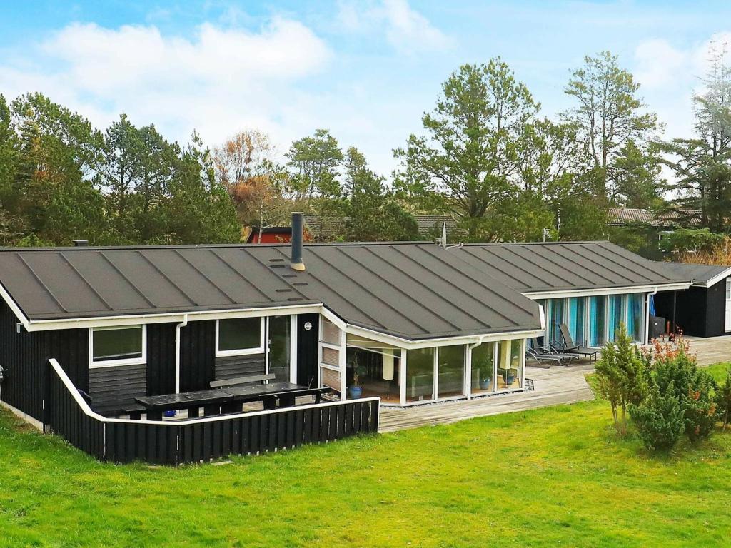 una casa con tetto nero e un cortile di Four-Bedroom Holiday home in Jerup 2 a Jerup
