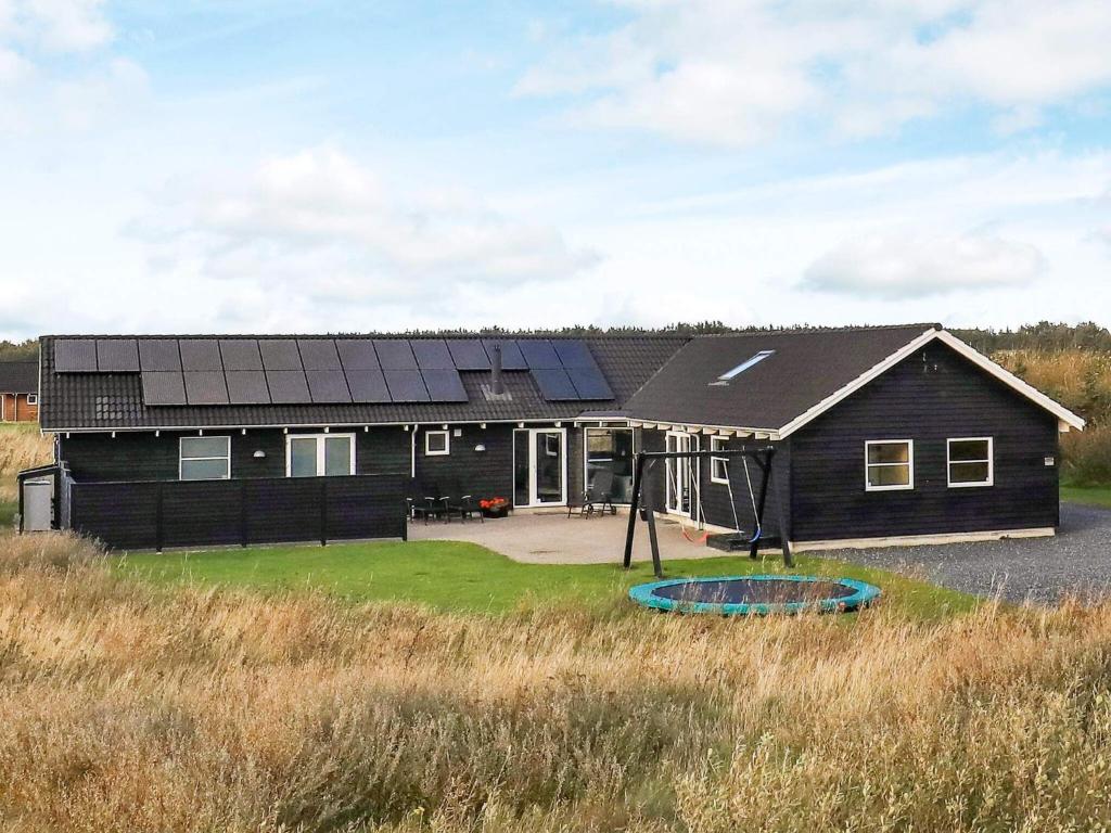 ein schwarzes Haus mit Sonnenkollektoren darauf in der Unterkunft 16 person holiday home in L kken in Nørre Lyngby