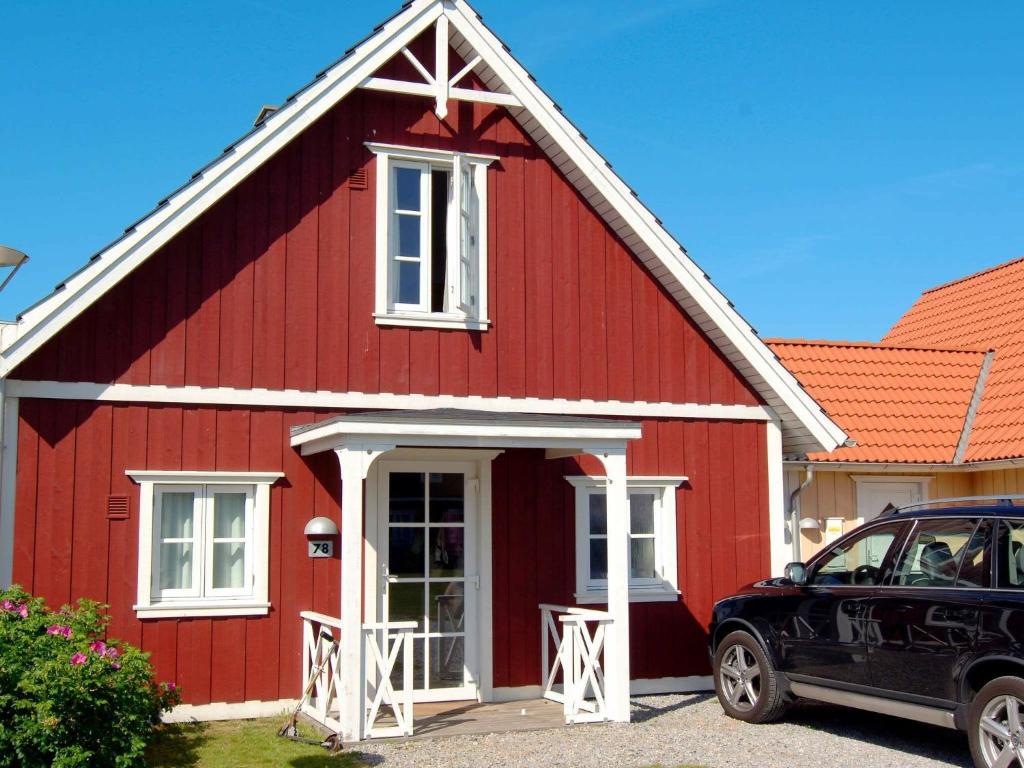 czerwony dom z samochodem zaparkowanym przed nim w obiekcie 6 person holiday home in Bl vand w mieście Blåvand