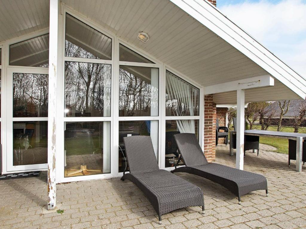 un patio con 2 sillas, una mesa y ventanas en 8 person holiday home in Hemmet en Hemmet