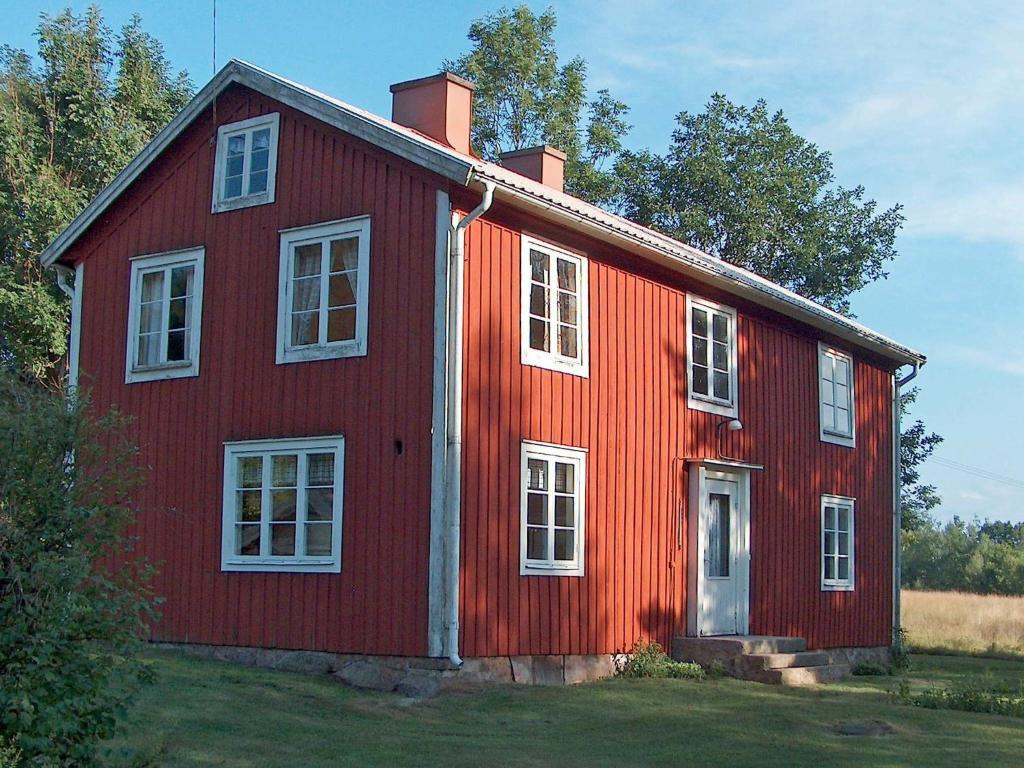 ein rotes Haus mit weißen Fenstern auf einem Feld in der Unterkunft 4 person holiday home in BRUA KULLA in Källekulla