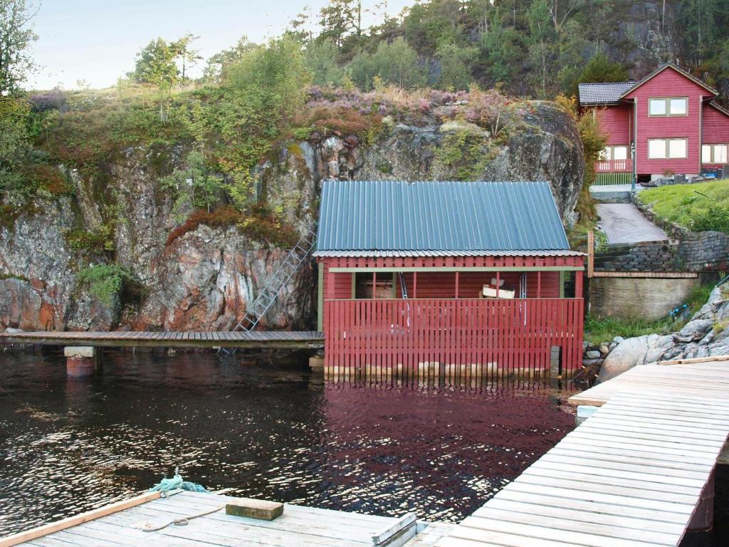 un edificio rojo con techo azul sobre un cuerpo de agua en 10 person holiday home in HOSTELAND-By Traum, en Hosteland