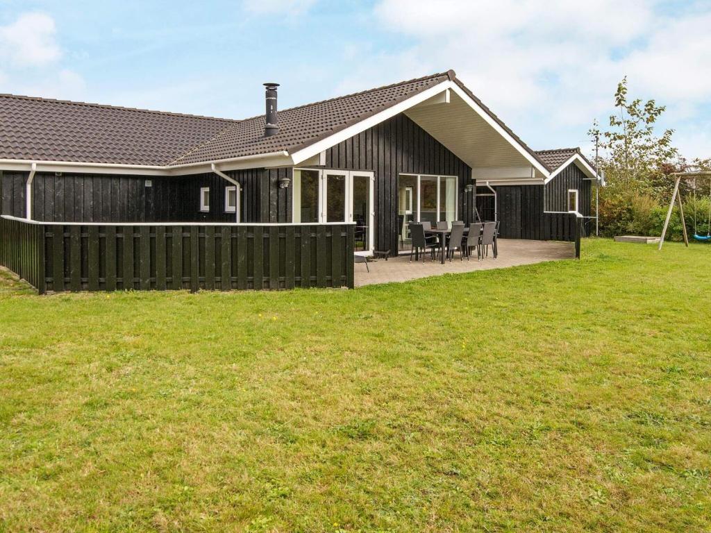 a house with a fence in front of a yard at 8 person holiday home in Tarm in Hemmet