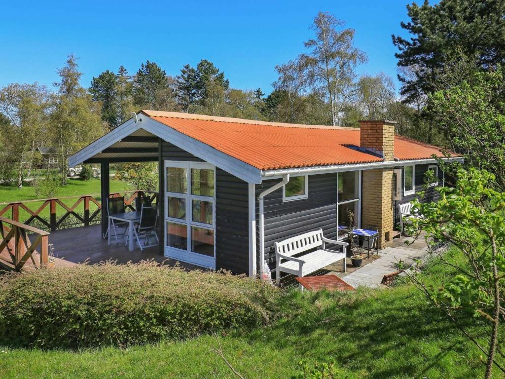 a small house with an orange roof and a deck at 5 person holiday home in Stege in Stege