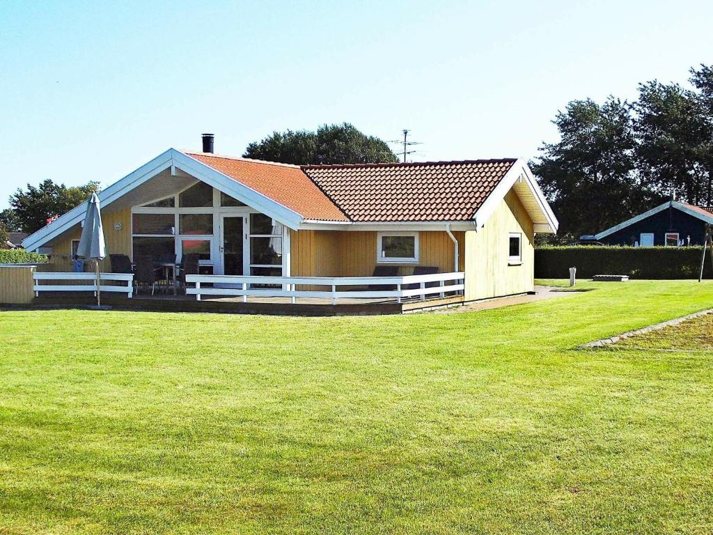 una pequeña casa amarilla con un patio de césped en 6 person holiday home in Nordborg, en Nordborg