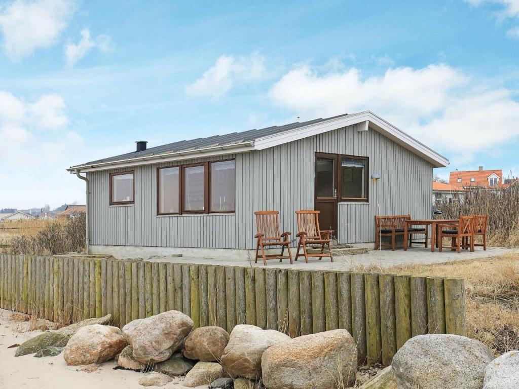 ein kleines Haus mit einem Zaun und einigen Steinen in der Unterkunft Holiday home Farsø in Sundsøre