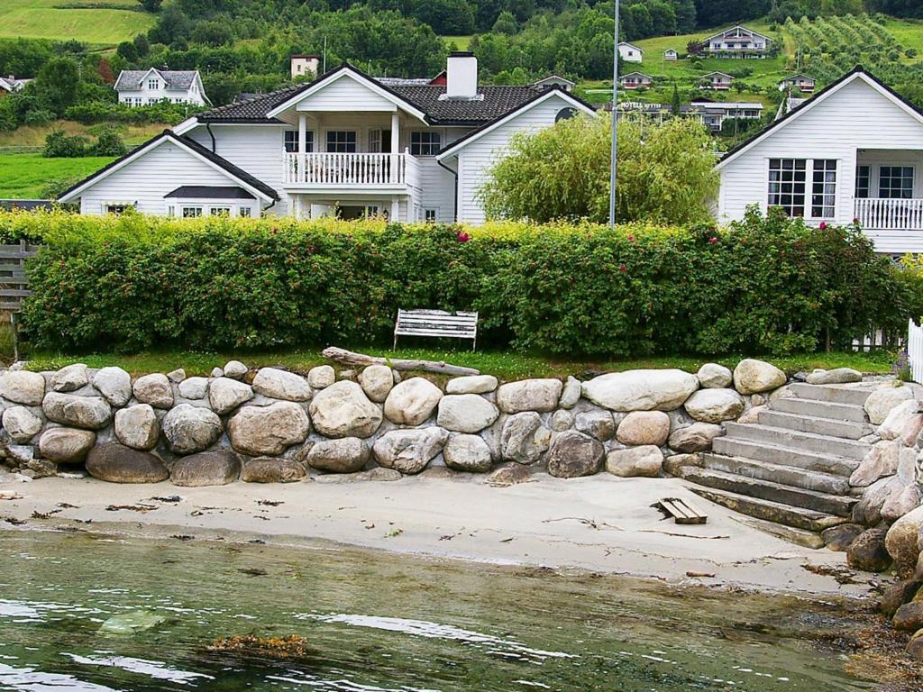 a house with a stone wall next to a body of water at Two-Bedroom Holiday home in Leikanger in Leikanger