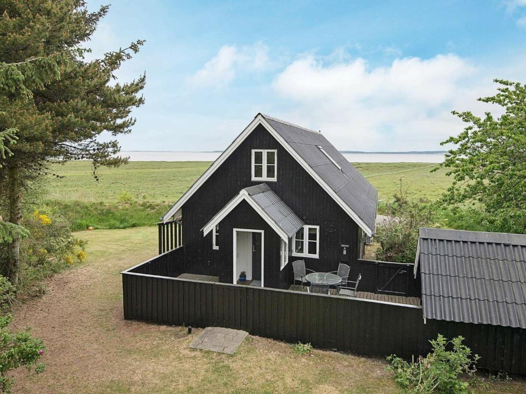 uma casa negra com um alpendre e uma mesa em Three-Bedroom Holiday home in Vejby 14 em Blåvand