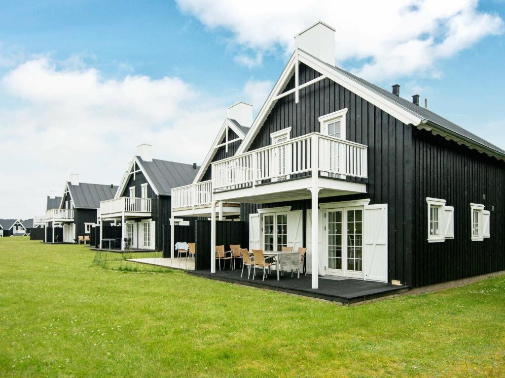 a black house with a white deck and a grass field at 8 person holiday home in Gjern in Gjern
